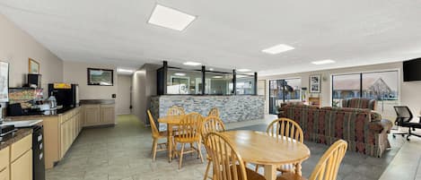 A spacious kitchen with a dining area, a bar, and a large window providing a view of the outdoors.