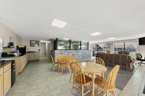A spacious kitchen with a dining area, a bar, and a large window providing a view of the outdoors.