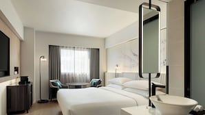 A hotel room with a large bed, a round table, a desk, and a modern bathroom with a large mirror and sink. - Courtyard by Marriott Tokyo Ginza Hotel (Tokyo)