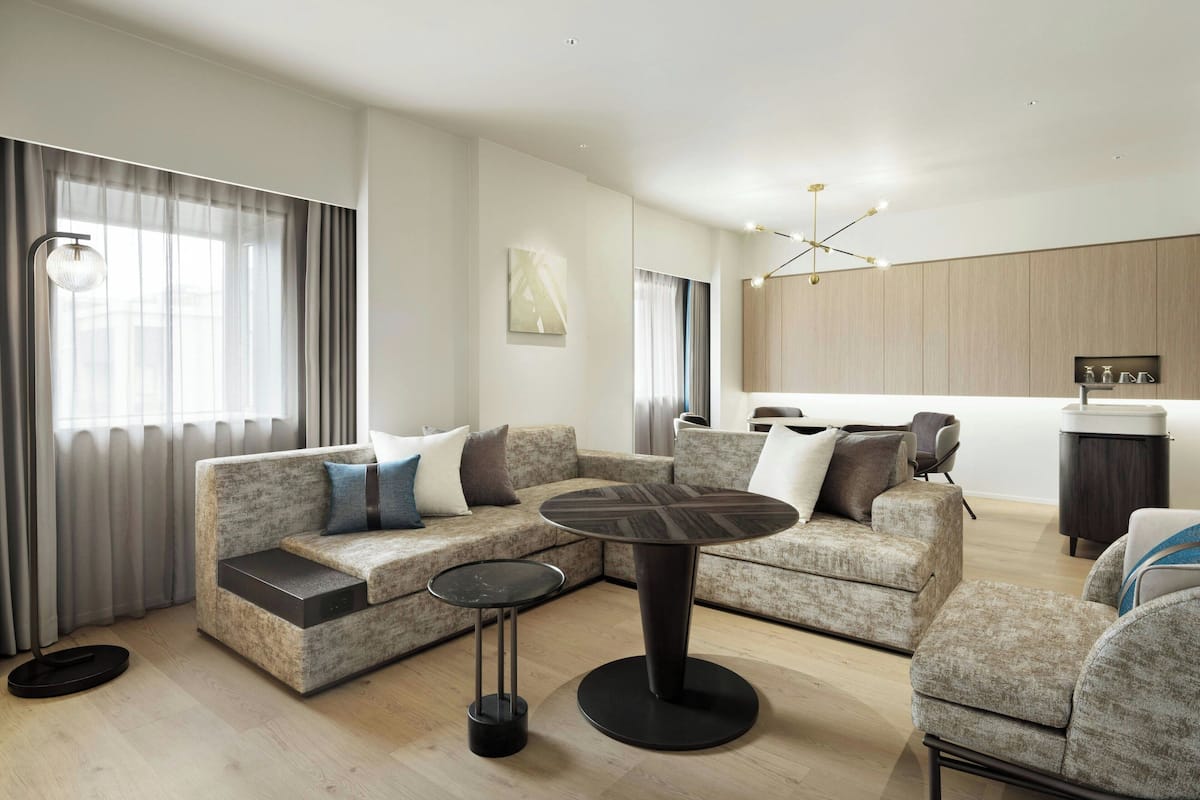 A modern living room with a sectional sofa, a round coffee table, and a dining area with a small table and chairs.