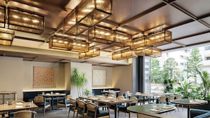 A modern restaurant with multiple dining areas, including booths and tables, and large windows offering a view of the city. - Courtyard by Marriott Tokyo Ginza Hotel (Tokyo)