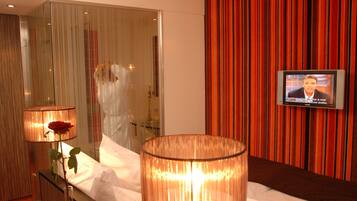 Ein Hotelzimmer mit einem Bett, einem Fernseher, einer Glasabtrennung und einem roten Vorhang.
