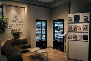 Un espace d’accueil de l’hôtel WestCord City Centre comprenant des sièges, un réfrigérateur rempli de boissons et un présentoir à magazines.