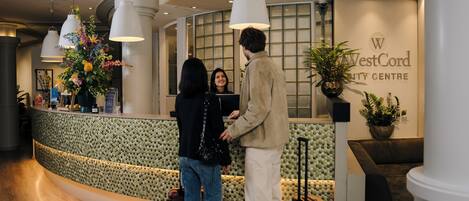 Een receptie met een gebogen balie, een grote kamerplant en een bord met daarop WestCord City Centre.