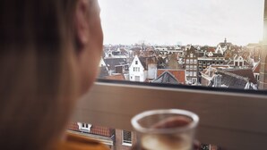 A view from a window overlooking a densely packed urban area with traditional architecture, including a prominent white building with a pointed roof. - WestCord City Centre Hotel Amsterdam (Amsterdam)