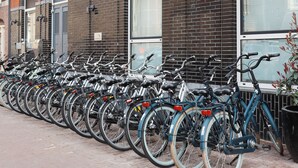 A row of bicycles parked outside a building with a sign indicating it is a hotel. - WestCord City Centre Hotel Amsterdam (Amsterdam)
