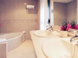 A bathroom with a bathtub, two sinks, a mirror, and a potted plant. - Rio Badajoz (Badajoz)