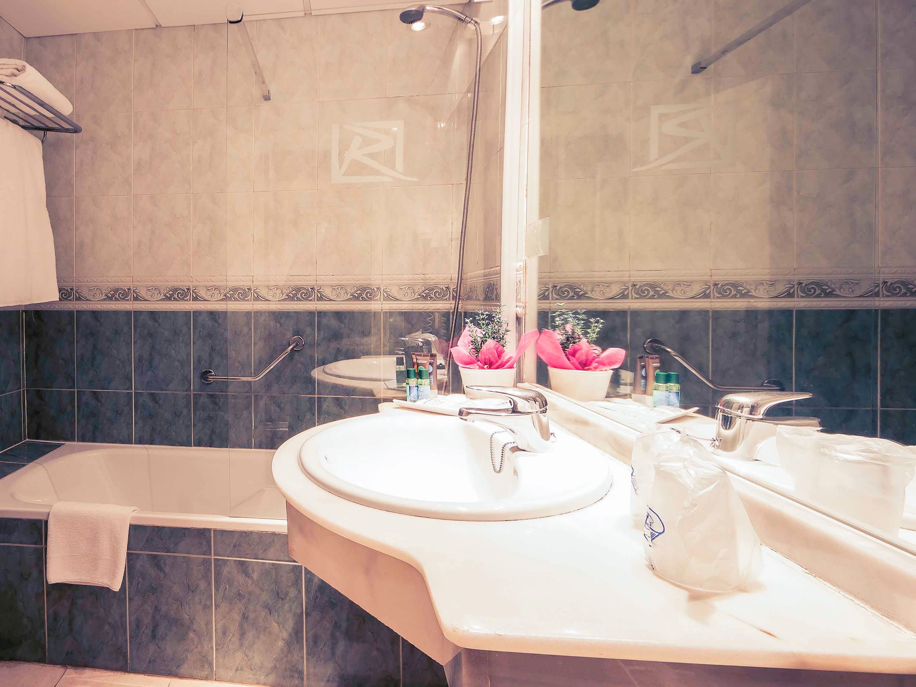 A bathroom with a bathtub, two sinks, a mirror, and a shower.