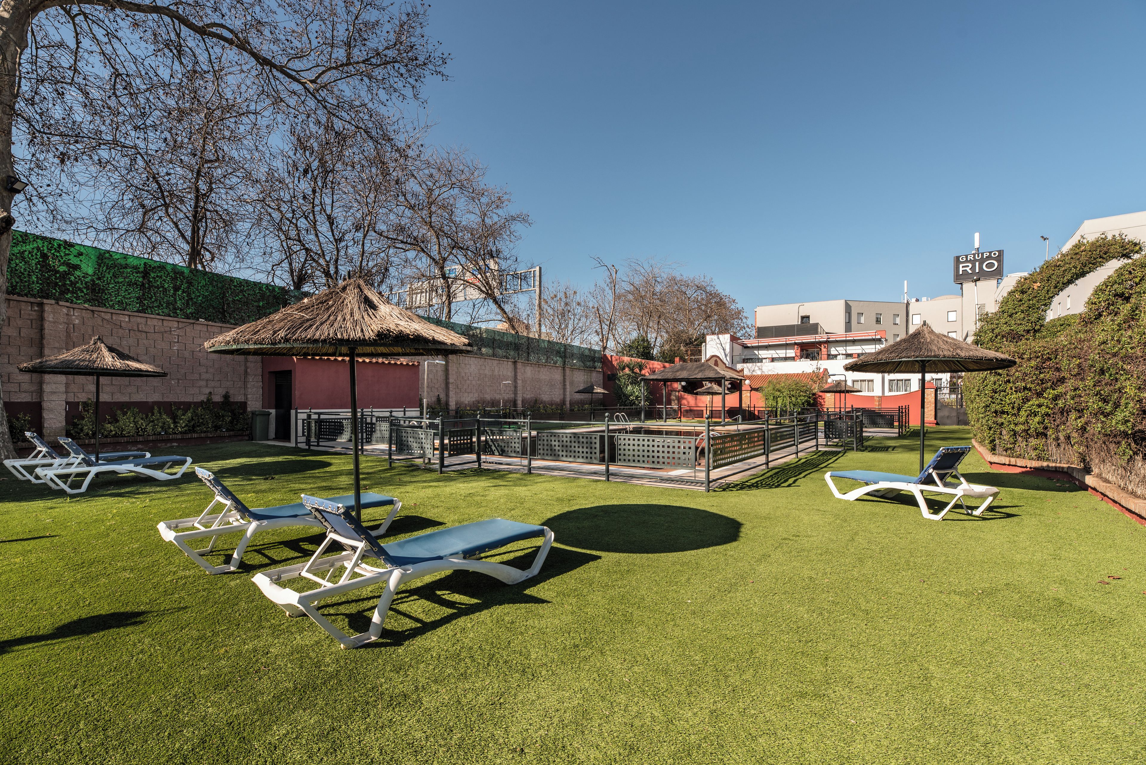 A well-maintained outdoor area with artificial grass, sun loungers, and a small pavilion.