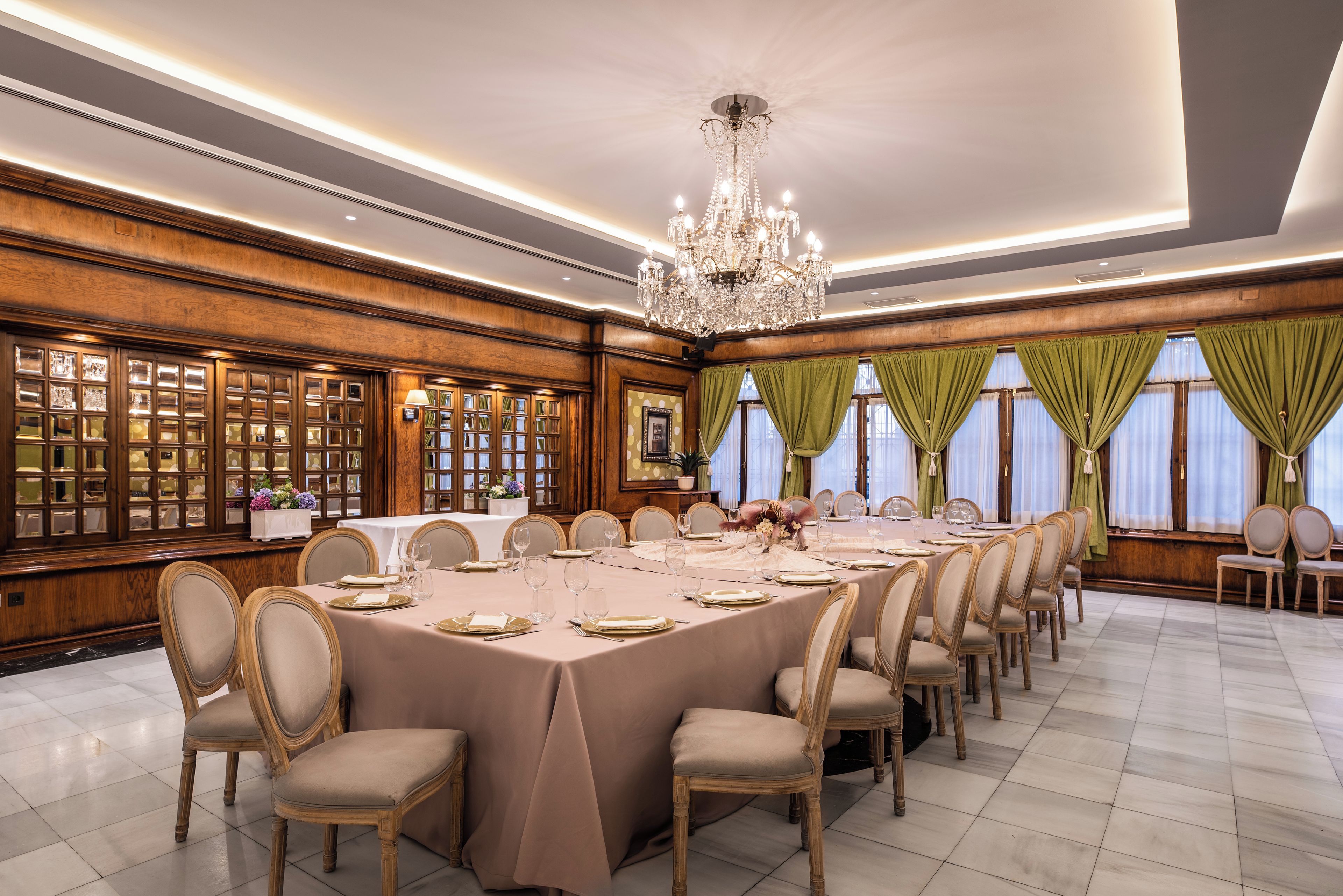 Comedor formal con una larga mesa dispuesta para una comida, rodeada de paneles de madera y un candelabro.