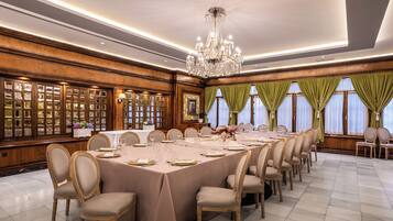 Comedor formal con una larga mesa dispuesta para una comida, rodeada de paneles de madera y un candelabro.