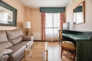 A living room with a sofa, a glass coffee table, a desk with a chair, a lamp, and a television. - Rio Badajoz (Badajoz)