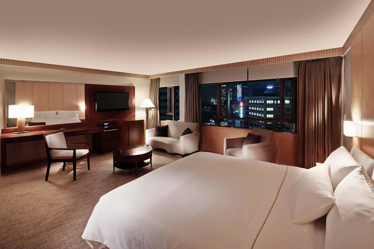 Een hotelkamer met een groot bed, een bureau met stoel, een bank en een televisie.