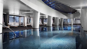 A spacious indoor swimming pool with clear blue water, large windows, and modern architecture.