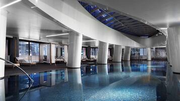 A spacious indoor swimming pool with clear blue water, large windows, and modern architecture.