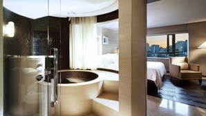 A modern hotel room with a glass-enclosed shower, a large bathtub, a bed, and a city view. - The Westin Josun Seoul (Seoul)
