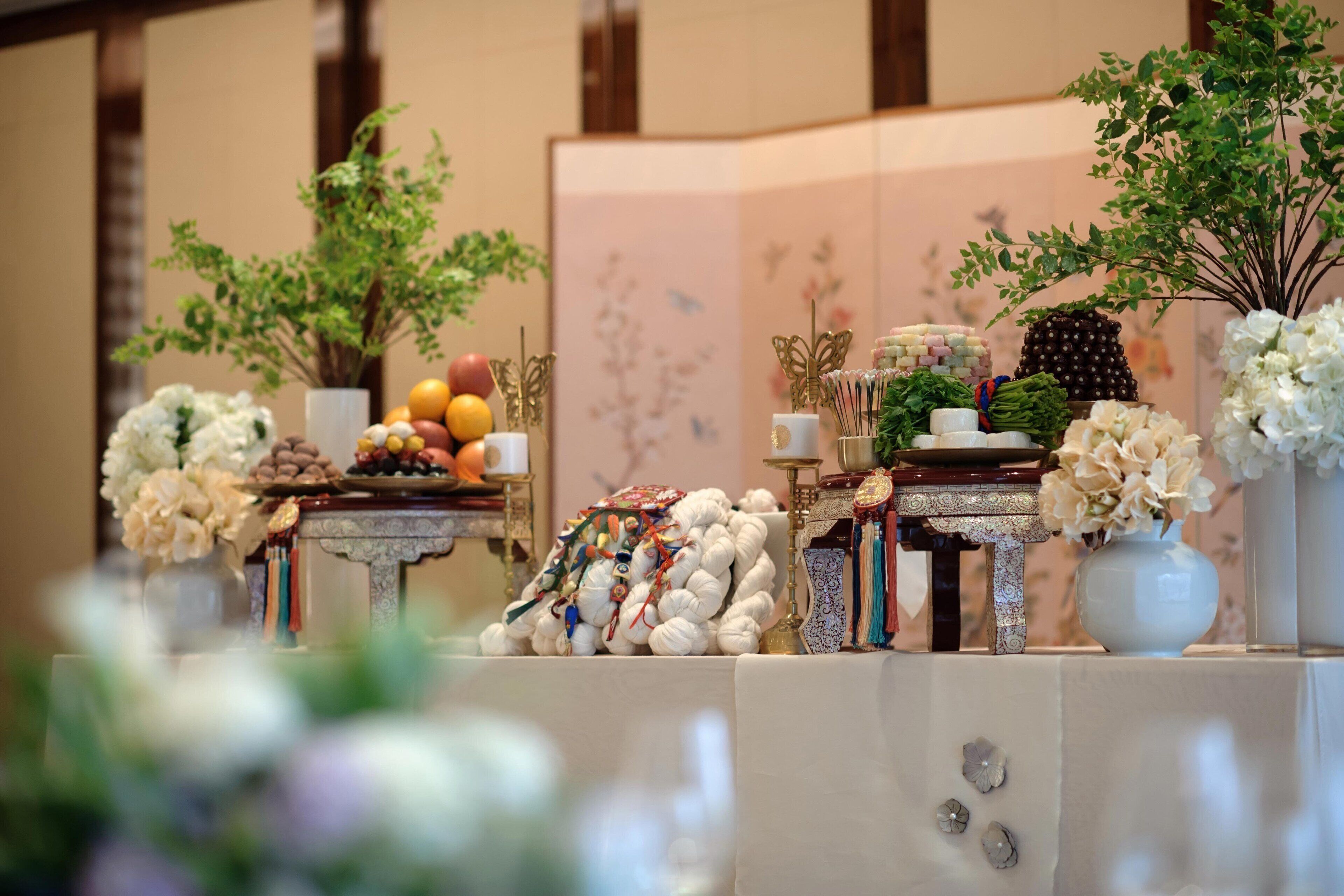 A table with various food items and decorations, including fruits, flowers, and a decorative tree.