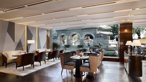 A modern dining area with a round table, chairs, and a view of traditional architecture. - The Westin Josun Seoul (Seoul)