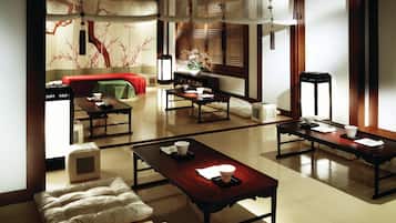 A traditional Japanese-style room with tatami mats, low tables, and a red sofa.