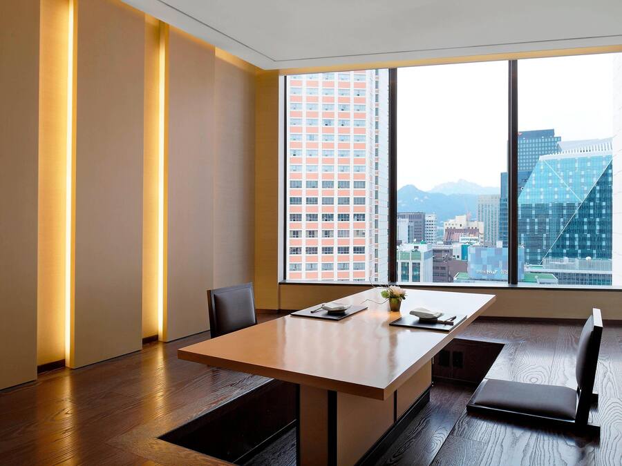 A modern office space with a large window, a wooden table, and a bench.