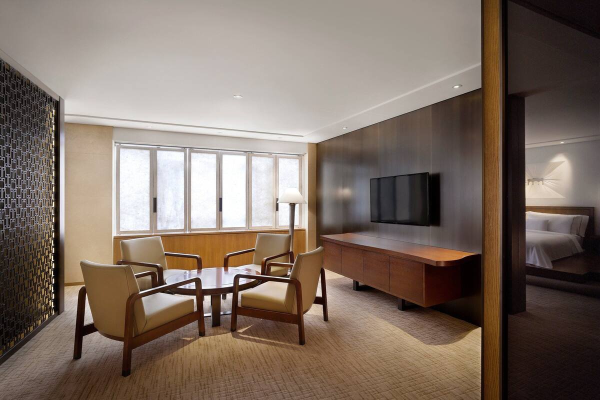 Een hotelkamer met een groot raam, een flatscreen televisie, een houten bureau en een bed.