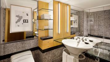 A modern bathroom with granite countertops, a large mirror, two sinks, and a glass shower enclosure.