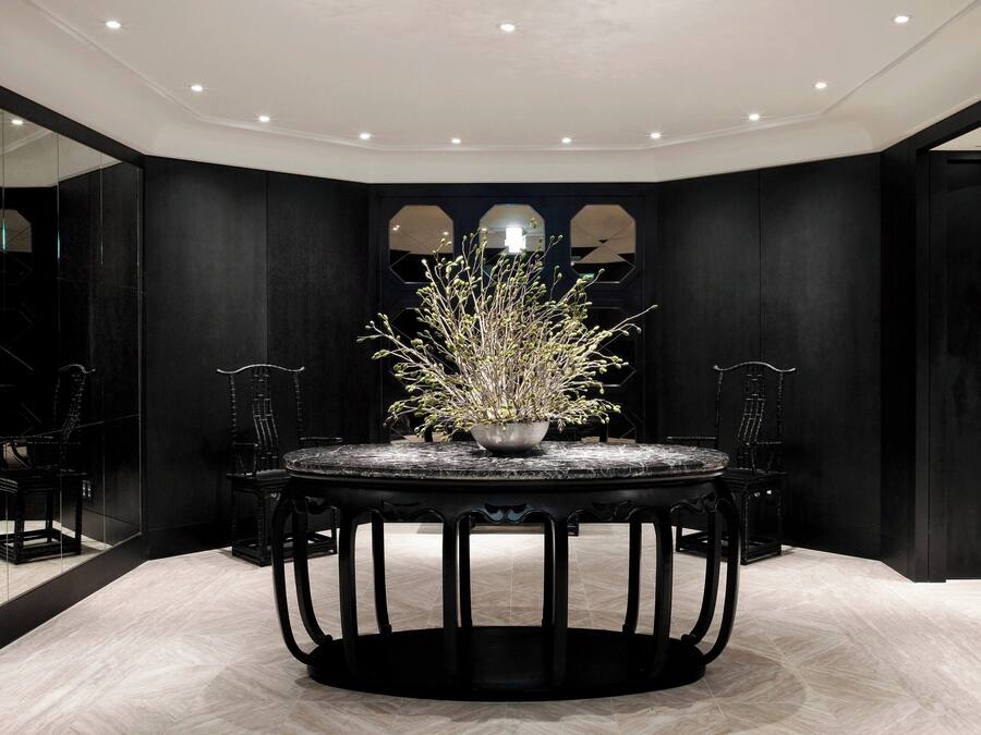 A modern dining area with a round table, chairs, and a decorative plant centerpiece.