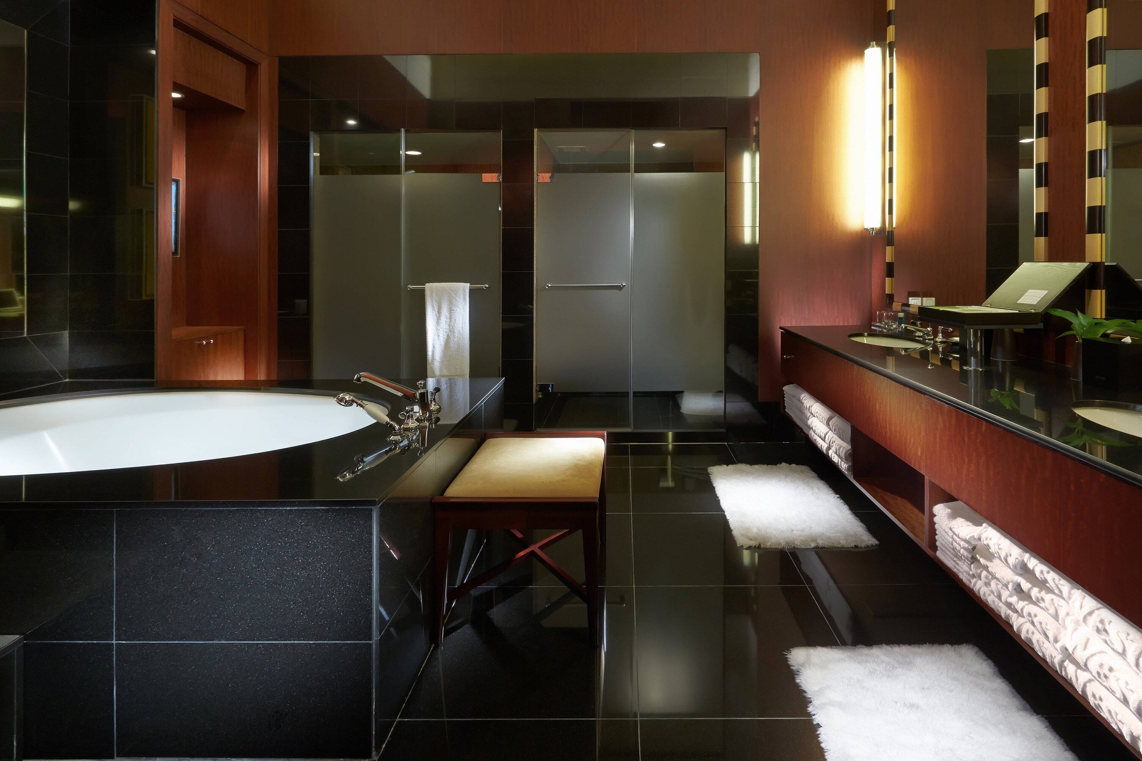Un baño moderno con una bañera grande, un banco de madera y un tocador con espejo.