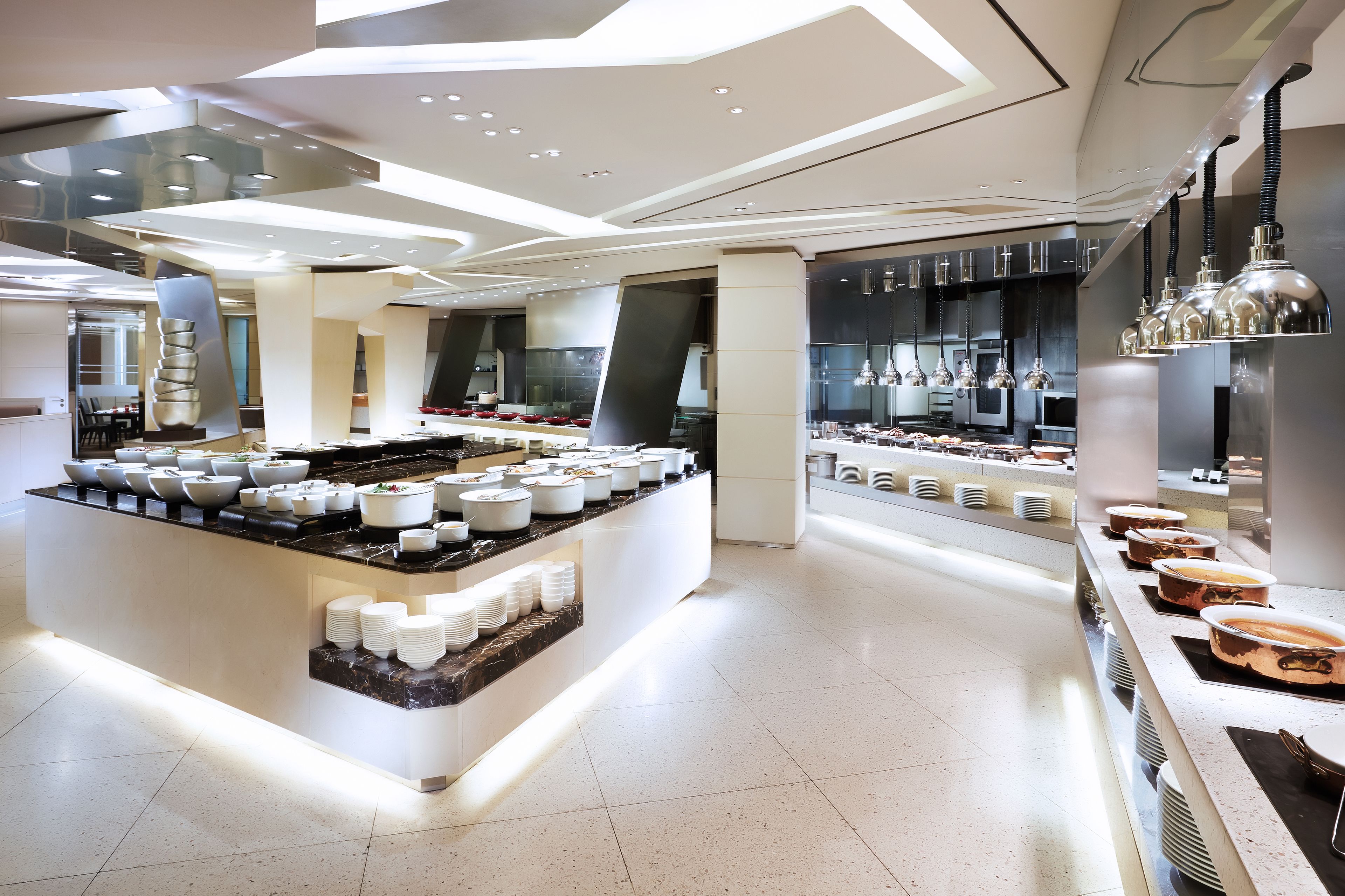 Cozinha moderna com ilha central, eletrodomésticos em aço inoxidável e diversos recipientes e pratos.