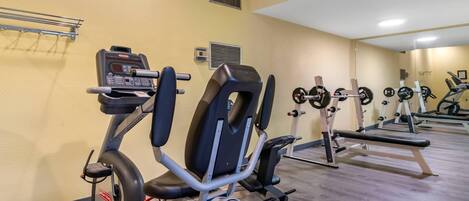 A gym with exercise equipment, a mirror, and a yellow wall.