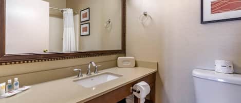Een badkamer met een wastafel, spiegel, toilet en fotolijstjes aan de muur.