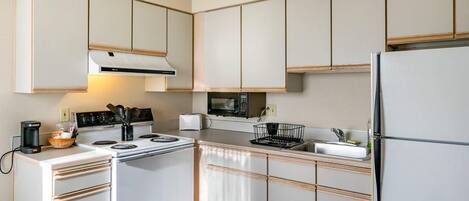 Una cocina moderna con armarios blancos, estufa, microondas y refrigerador.