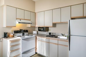 A modern kitchen with white cabinets, a stove, a microwave, and a refrigerator. - Comfort Inn & Suites Seattle North (Seattle)