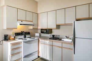 Uma cozinha moderna com armários brancos, fogão, micro-ondas e geladeira.