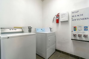 Ein Waschbereich mit Waschmaschine, Trockner und Wandspender für Waschmittel, Bleichmittel und Weichspüler.