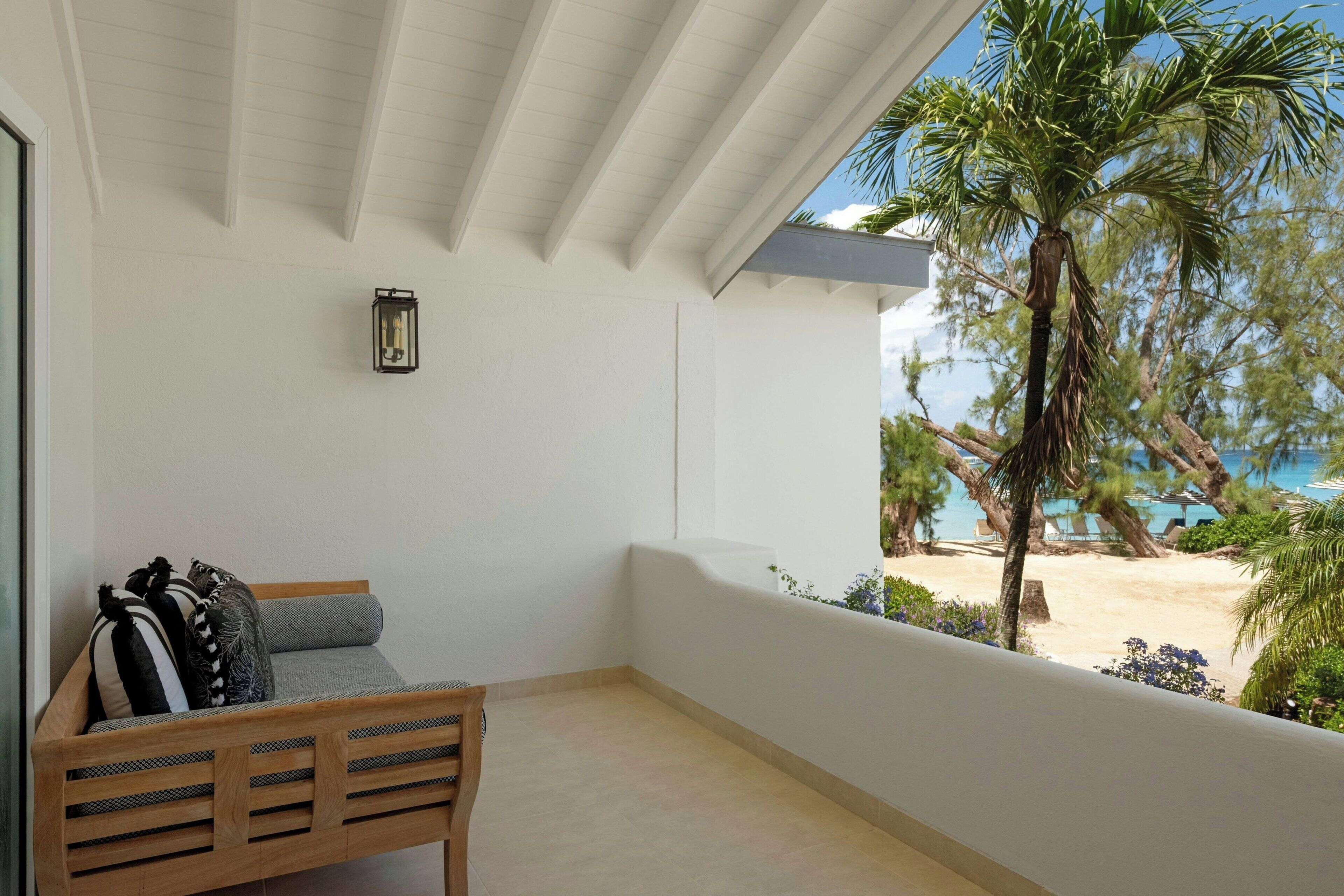A balcony with a wooden bench, a small table, and a wall-mounted light fixture.