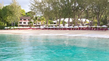 En la playa, playa de arena blanca, camastros y sombrillas