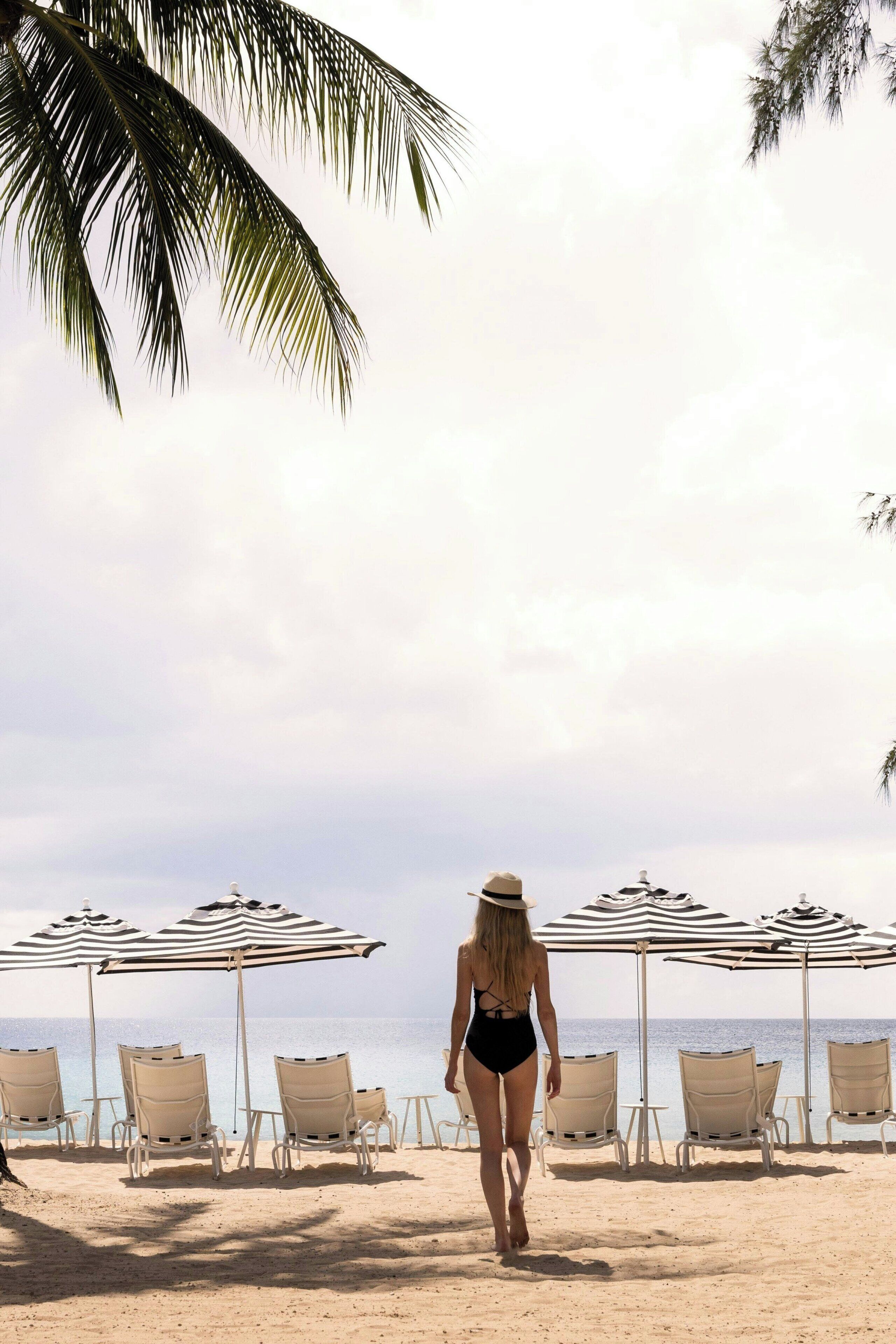 Una playa con sillones de descanso y sombrillas a rayas.