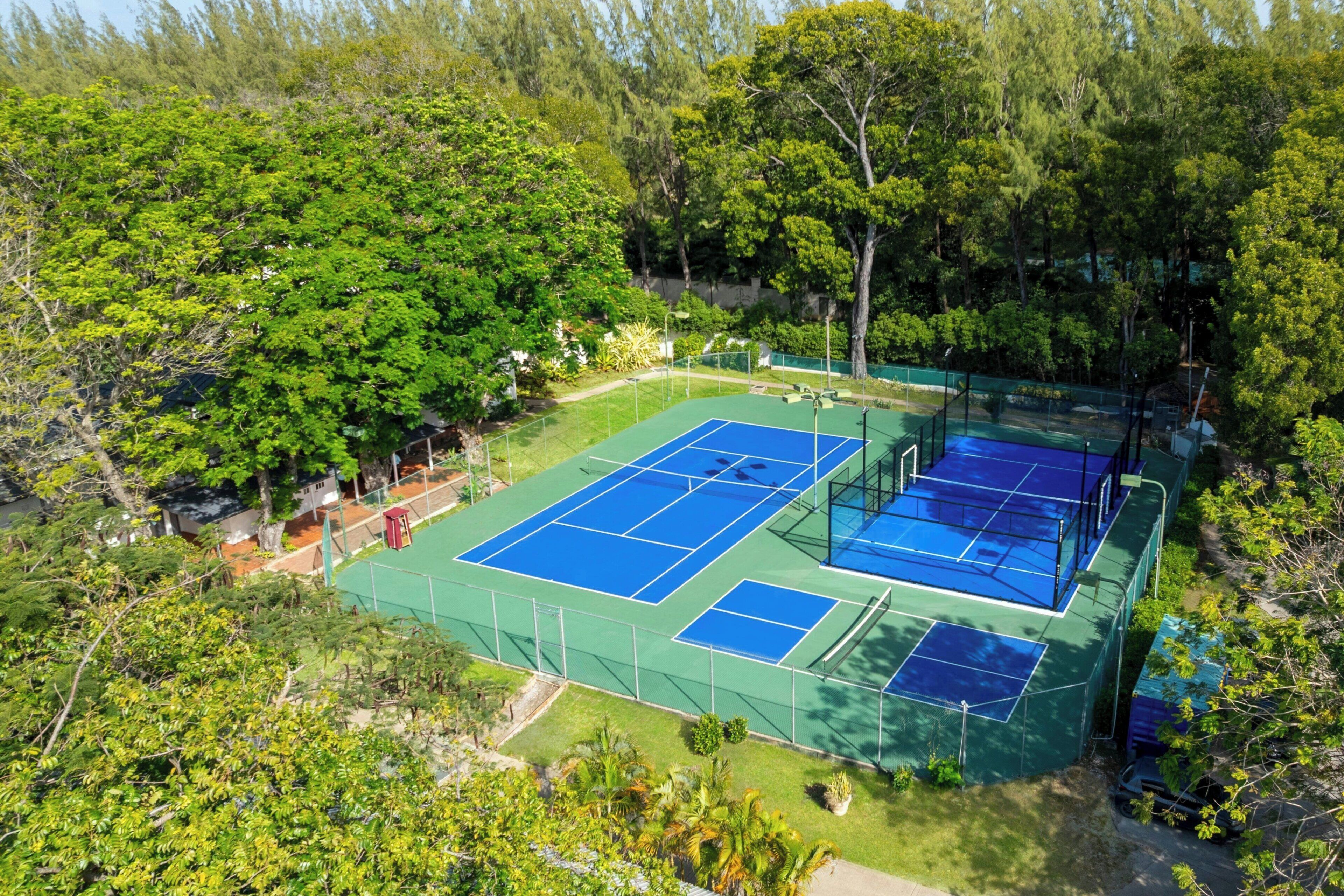 Un court de tennis en plein air, entouré d’une végétation luxuriante.