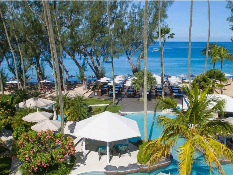 Un resort con piscina, sombrillas y vista al océano.