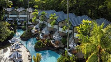 Un complejo turístico con varias villas, una piscina central y zonas de estar al aire libre con sombrillas.