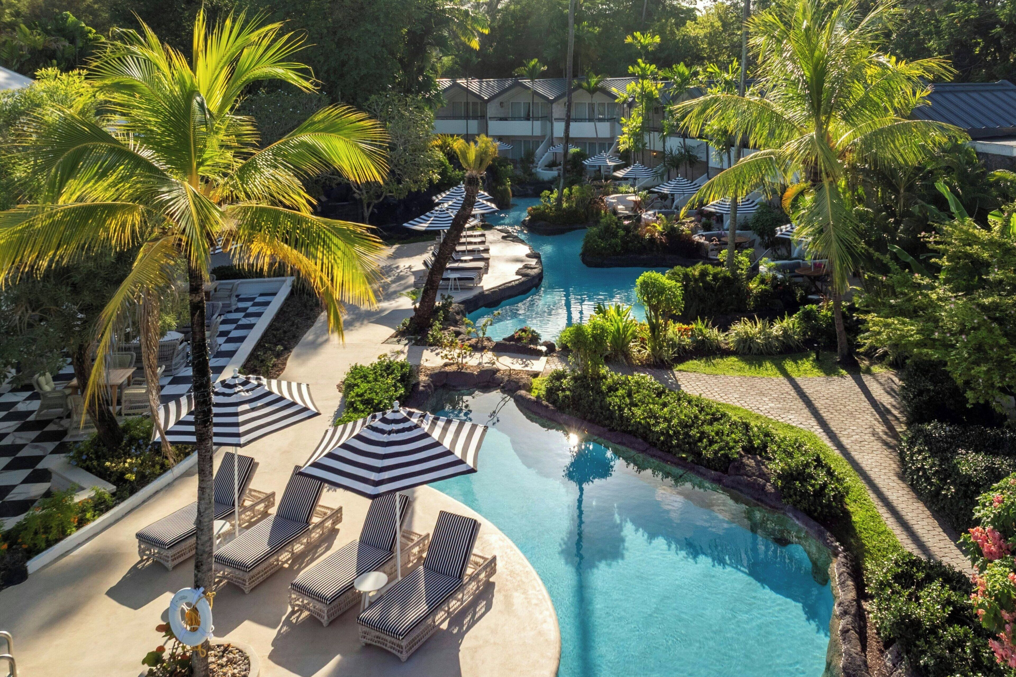 Un resort con piscina central, sillas de descanso y palmeras.