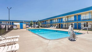 Ett motell med en swimmingpool, utomhusmöbler och ett inhägnat område.