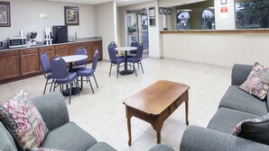 En hotellobby med en matplats, en receptionsdisk och en sittgrupp med soffor och fåtöljer.