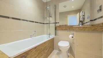 Une salle de bain moderne avec une douche à parois de verre, une baignoire sur pied et des toilettes.