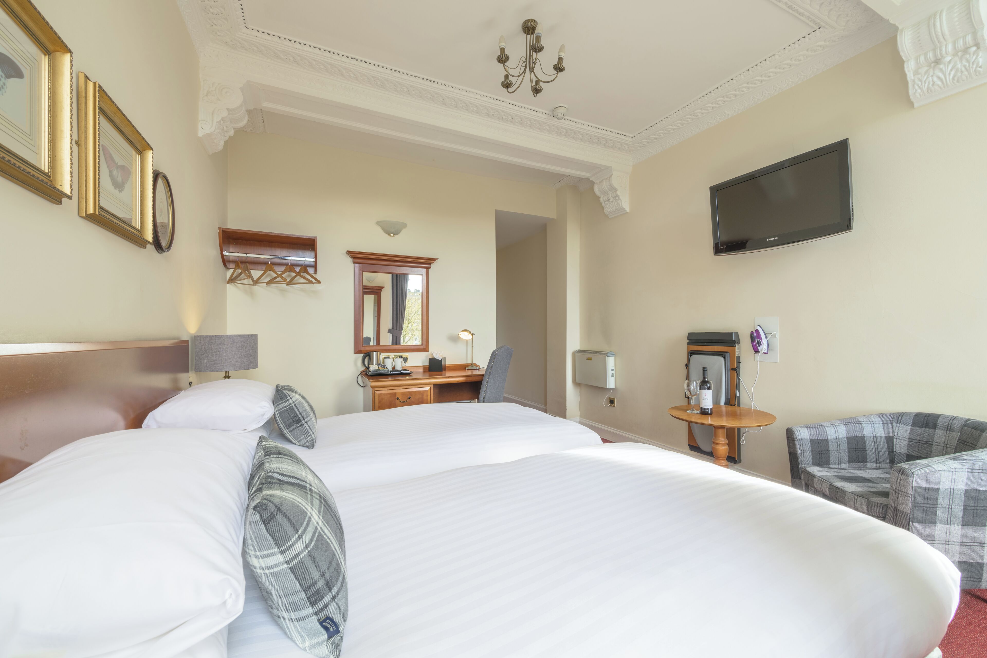 A hotel room with a large bed, a desk, a chair, a television, and a mirror.