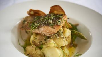 A plate of food with a piece of meat, potatoes, and a garnish.