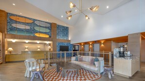 Um hall amplo com uma mesa de recepção, área de estar e uma cozinha visível ao fundo.