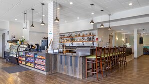 Uma área de bar moderna com balcão, prateleiras cheias de garrafas e cadeiras de madeira.