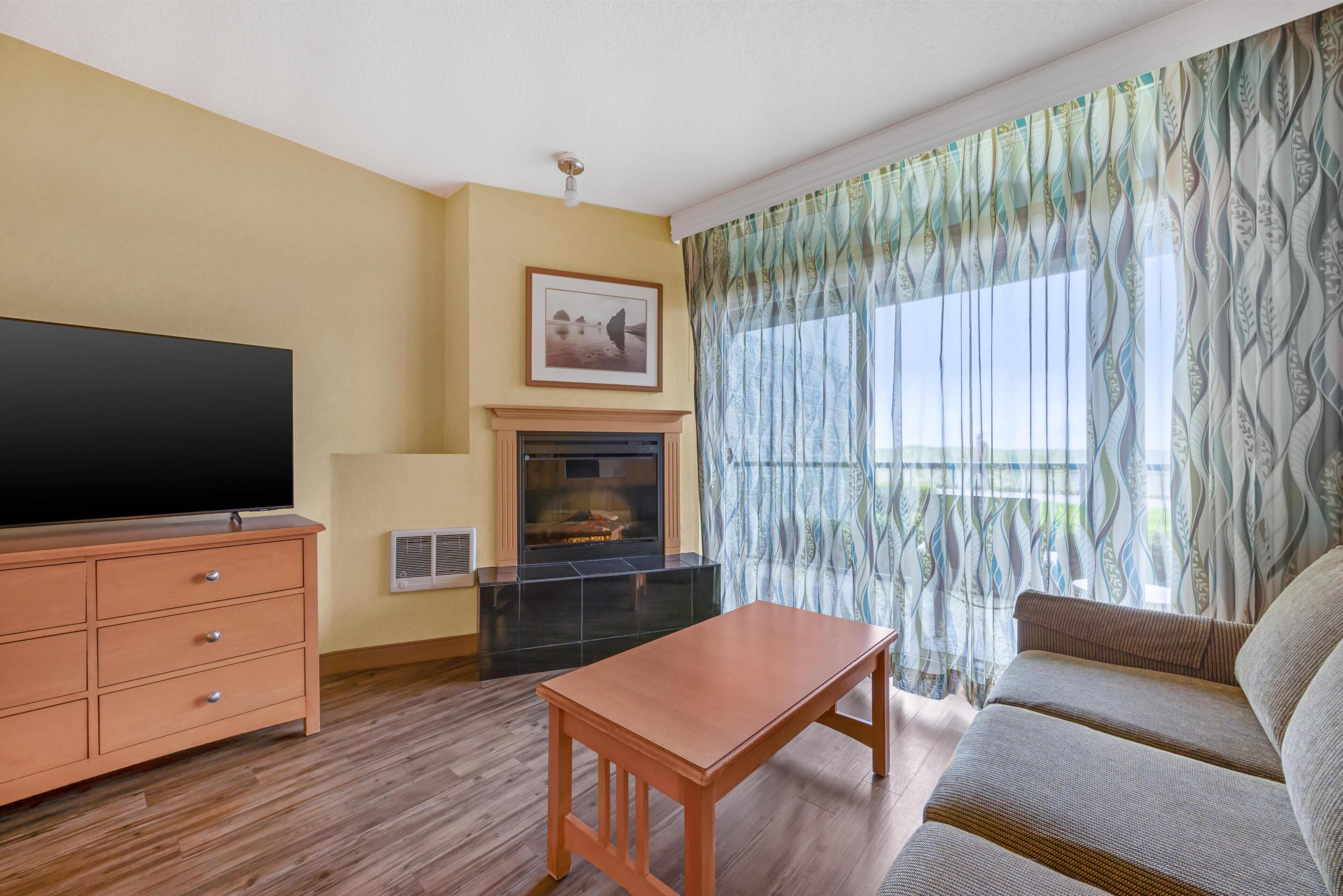 Una sala de estar con televisor de pantalla plana, chimenea, sofá y cortinas estampadas.